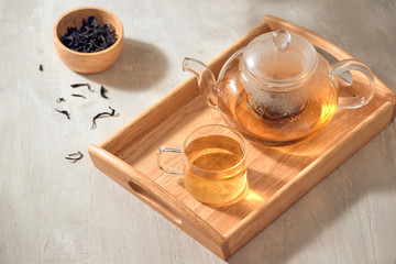 Tea in a transparent cup and teapot on a wooden background - obrazy, fototapety, plakaty