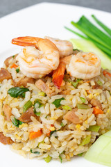 Fried rice with shrimp and Chinese sausage in white plate on concrete table.