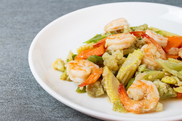 Fried vegetables with shrimp in oyster sauce for healthy in white dish on concrete table.