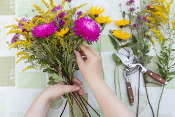 Hands of florist making autumn bouquet with aster and yellow flowers 