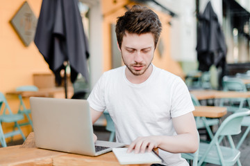 man checking notebook and laptop concentrated outdoors