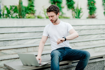 Obraz premium man concerned about time working remotely as freelancer outdoors