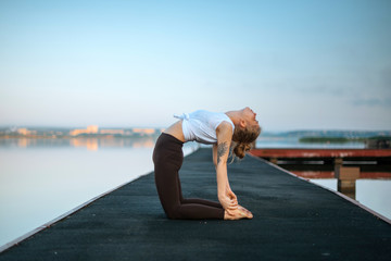 Girl practice yoga early morning on pier