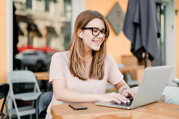 woman working remotely with laptop and phone in cafe