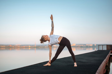 Girl practice yoga early morning on pier