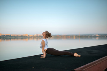 Girl practice yoga early morning on pier