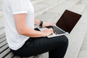 Naklejka premium woman typing on laptop keyboard on the street