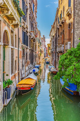 Obraz na płótnie Canvas Venice, Veneto, Italy July 24 2017 a view down a tributary canal with boats moored along side houses