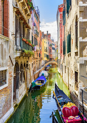 Fototapeta na wymiar Venice, Veneto, Italy July 24 2017 a view down a tributary canal with gondola and boats moored along side houses
