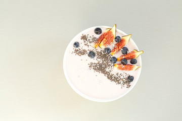 Healthy breakfast berry smoothie bowl topped with figs, coconut and chia seeds. Top view of a smoothie bowl with fresh ripe blueberry, figs, yogurt, coconut and chia. The concept of healthy eating and