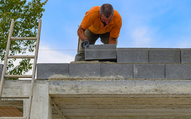 Bricklayer putting down another row of bricks in site