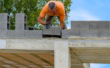 Bricklayer putting down another row of bricks in site