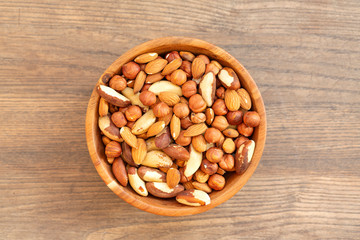 Assortment of nuts: hazelnuts, almonds and Brazil nuts. Top view of mixed nuts in a wooden bowl on wooden table. 