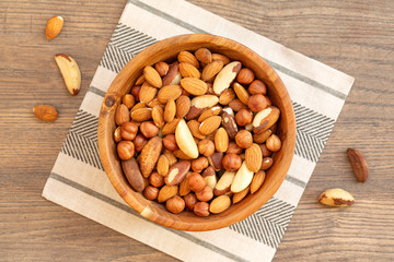 Assortment of nuts: hazelnuts, almonds and Brazil nuts. Top view of mixed nuts in a wooden bowl on wooden table. 