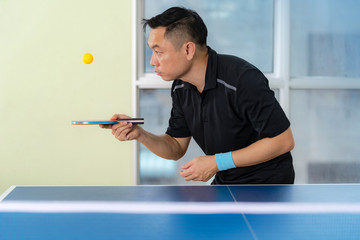 Ping pong table, Male playing table tennis with racket and ball in a sport hall