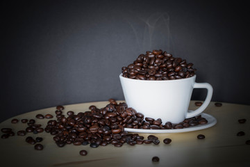 Coffee bean in white coffee cup on old wood. Background 