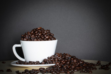Coffee bean in white coffee cup on old wood. Background 