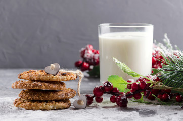 Tasty homemade cookies, glass of warm  milk adn Christmas decorations on the grey table