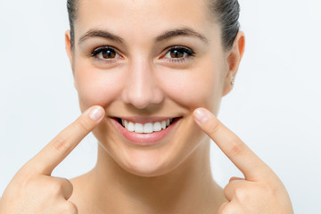 Attractive young woman showing pointing with fingers on sagging wrinkles on cheek.