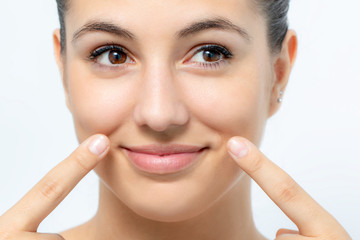 Cute girl pointing at wrinkles along cheek.