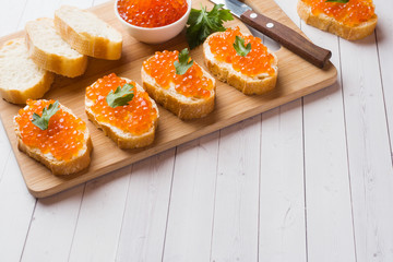 Sandwiches with red salmon caviar on a wooden Board. White table top.