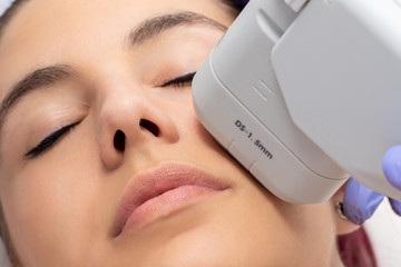 Woman receiving high intensity focused ultrasound treatment on face.