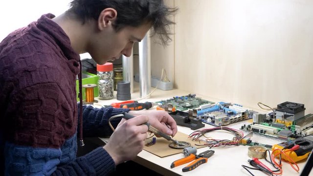 Student working with electronic components at home office using soldering iron