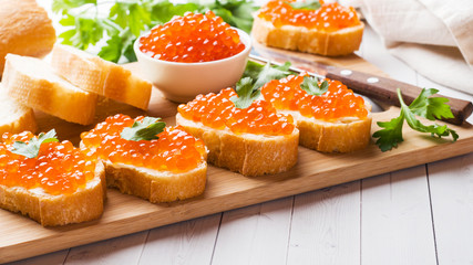 Sandwiches with red salmon caviar on a wooden Board. White table top.