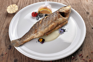 Fried Sibas fish on a white plate