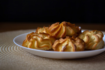 Profiteroles with cream in a plate stand on a wicker napkin