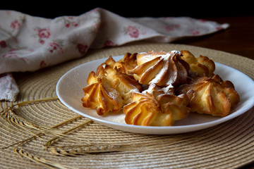 Profiteroles with cream in a plate stand on a wicker napkin