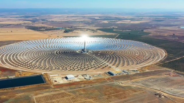 Aerial view with a drone of a large and circular solar thermal plant uses mirrors that focus the sun's rays on a collection tower to produce renewable and pollution-free energy - environmental concept