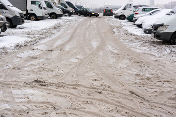 Minsk, Belarus, Circa March 2019: cars standing in two rows in parking lot in winter time, messy snowy roar in city