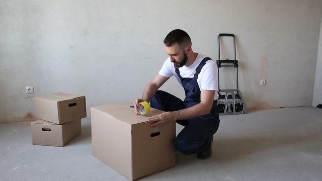 Man seals the box with adhesive tape