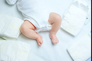 Obraz na płótnie Canvas Feet of newborn baby on changing table with diapers. Cute little girl or boy two weeks old. Dry and healthy body and skin concept. Baby nursery.