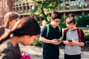 Classmates using smart phone at schoolyard