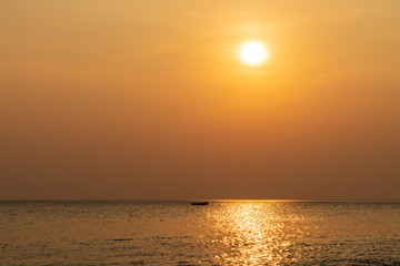 Sunset in Costa Rica along pacific coast with single small boat on the ocean surface