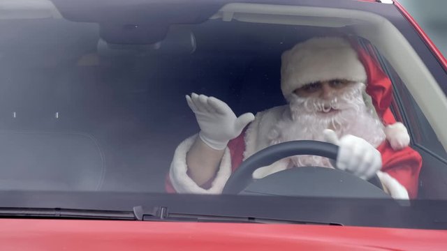 Funny santa dances at wheel of car.