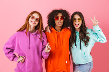 Three happy young girls wearing colorful hoodies standing