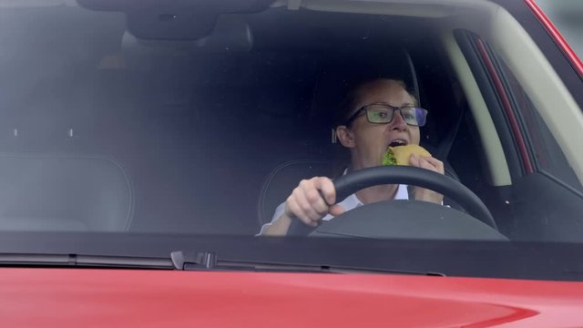 Business woman eating cheeseburger while driving car.