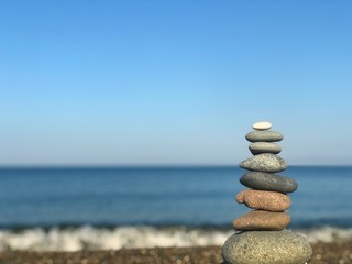 Fototapeta na wymiar Marine theme: stones on the shore. The stones are stacked in a pyramid against the background of the sea. Pyramid of small stones on the beach. The concept of harmony of balance and meditation. 