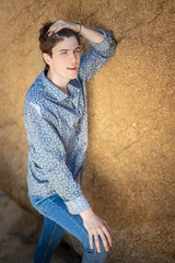 young man with jeans and white shirt among rocks