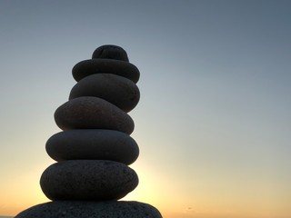 Marine theme: stones on the shore. The stones are stacked in a pyramid against the background of the sea. Pyramid of small stones on the beach. The concept of harmony of balance and meditation. 