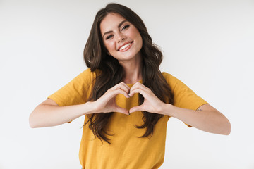 Image of charming brunette woman wearing casual clothes smiling and showing heart shape with fingers
