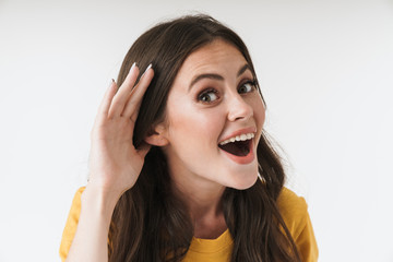 Image of pleased brunette woman wearing casual clothes smiling and trying to hear