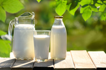 Glass and jug of fresh milk on wooden table