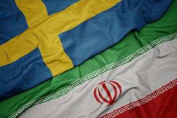 waving colorful flag of iran and national flag of sweden. © luzitanija