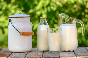Glass and jug of fresh milk on wooden table