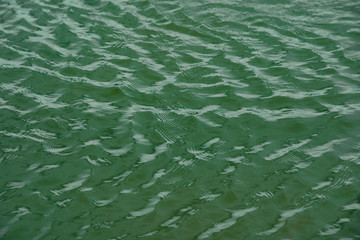 green water surface By wind.Water surface ruffled by light wind with small waves running diagonally, with reflections and graduated from light and green tones.soft focus.