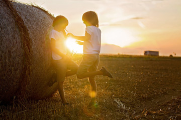 Happy children, playing on haystacks summertime
